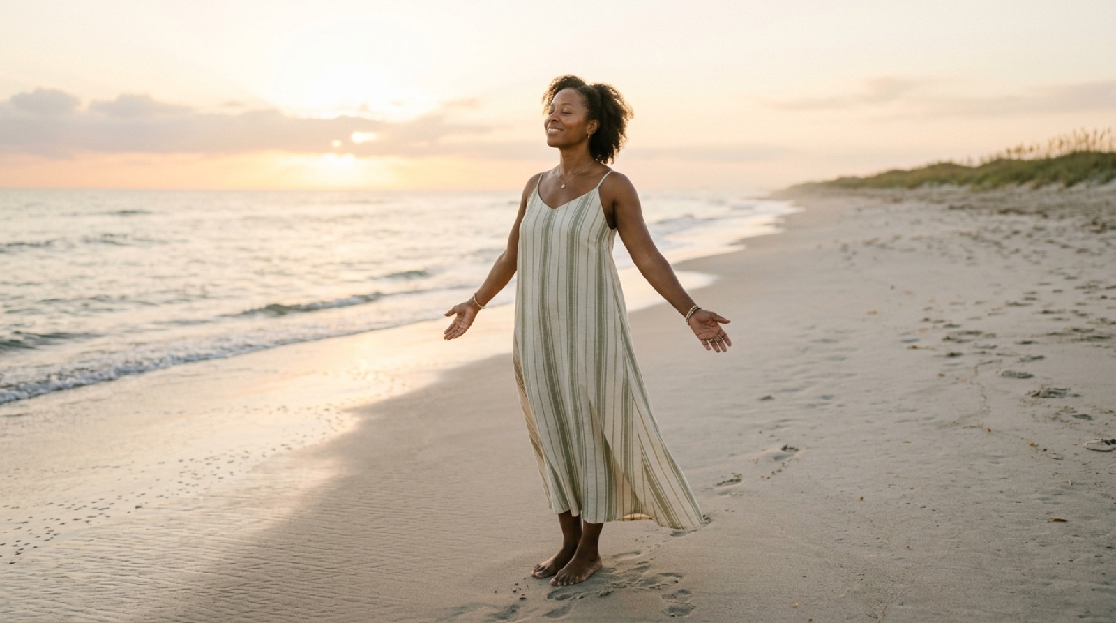 A woman standing peacefully on a Florida beach at sunrise with her arms open